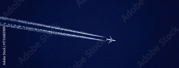Fototapeta Airplane flying high above clear blue sky leaving white contrails behind during daylight hours