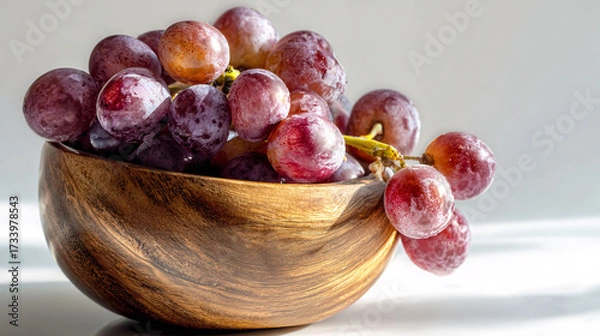 Fototapeta Fresh red grapes overflowing from a rustic wooden bowl, healthy eating concept.