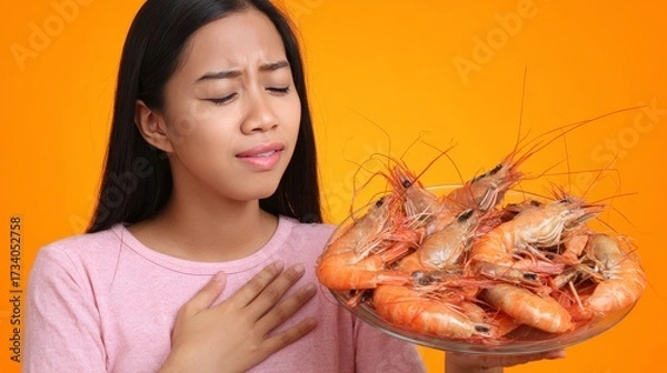 Fototapeta Young woman experiencing severe food allergy reaction with itching and redness after eating shrimp. Symptoms include rash, abdominal pain and breathing difficulty showing seafood allergy health risks