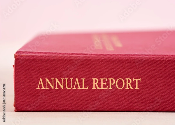 Fototapeta Red annual report with golden letters lying on a white surface