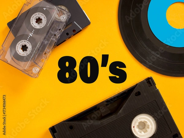 Fototapeta Audio Cassette, Vinyl Record and VHS Representing the 80's on Yellow Background