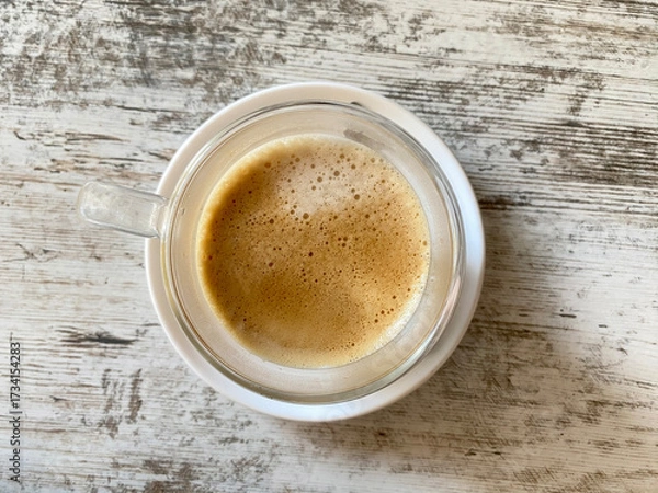 Fototapeta Cup of coffee with foam on wooden table. Coffee break.  Top view. 