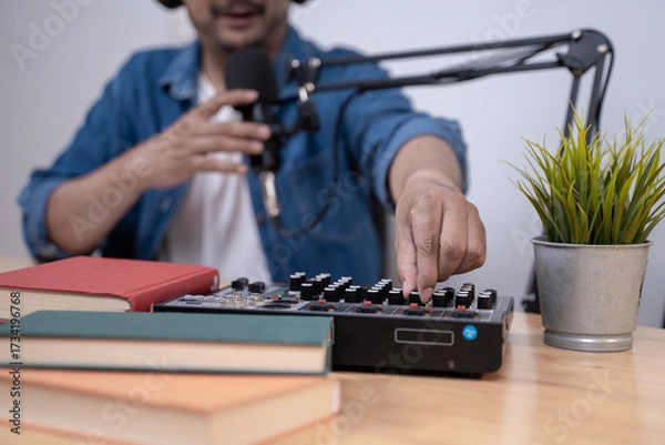 Fototapeta Close-up of young man recording a podcast with microphone and headphones, modern content creation and broadcasting concept.