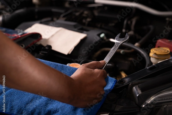 Fototapeta Young man fixing car engine by himself at home, concept of DIY repair, maintenance, and saving money on vehicle service.