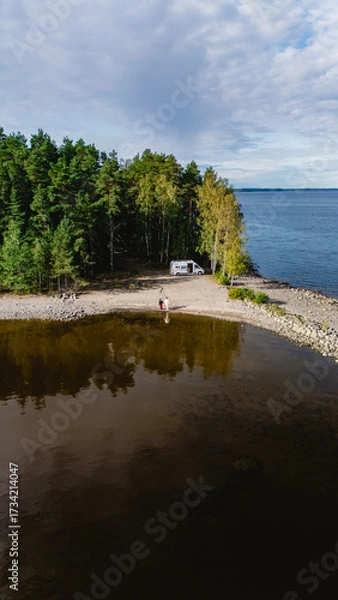 Fototapeta Travelers enjoy the peaceful beauty of Lake Saimaa, surrounded by lush forests and calm waters. A perfect day for a getaway in Finland, ideal for relaxation and adventure.