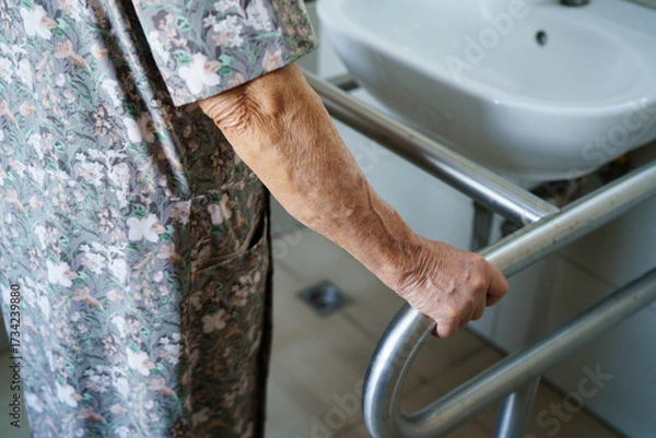 Fototapeta Asian elderly woman patient use toilet support rail in bathroom.