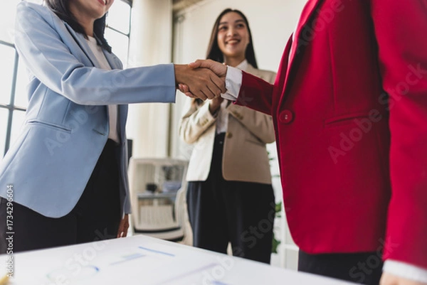 Fototapeta Businesswoman shaking hands with colleague after meeting in office. Business people shaking hands in the office for a deal, collaboration. Employees with handshake for welcome or greeting.