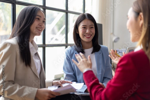 Fototapeta Group of young Asian businesswoman talking in the office. Working with happy coworkers meeting and discussing in the office.