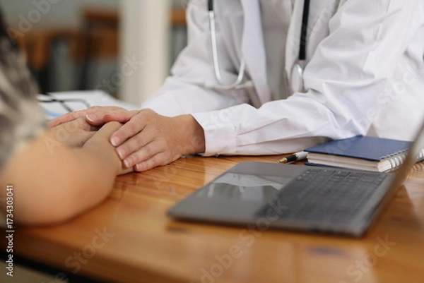 Fototapeta Female doctor comforting patient by holding her hand. Caring doctor holds a patient's hand with empathy and trust in a healthcare setting, showing the importance of human connection.
