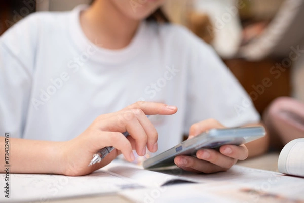 Fototapeta スマートフォンを見ながら勉強をする中学生
