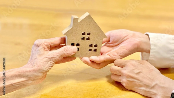 Fototapeta 家の小物を女性に渡す高齢女性_黄土色背景