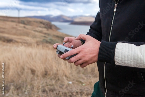Fototapeta Man holding a remote control of a drone in the field. Close-up.