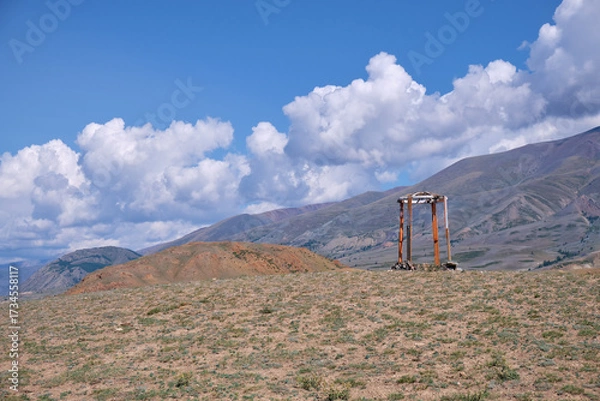 Fototapeta Religious wooden construction in Altai mountains. In background Kurai mountain range under blue sky and clouds.