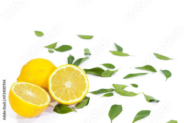 Fototapeta Whole and Halved Lemons with Leaves on a White Background