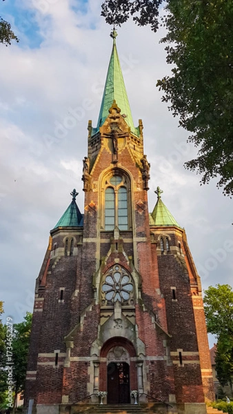 Obraz The magnificent brick tower of the historic Church of the Visitation in Sucha Beskidzka, Poland, glows in the warm light of the setting sun, highlighting its beautiful neogothic architectural details.