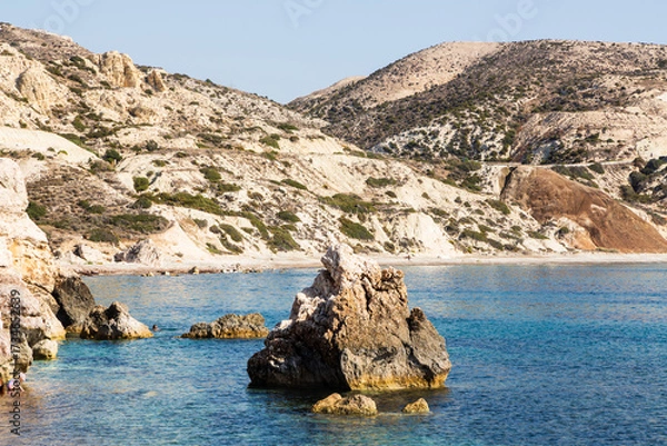 Fototapeta Paphos, Cyprus - 10 November 2023: Small toddler playing in the water near Aphrodite’s rock is a sea stack in Paphos, Cyprus. A birthplace of Aphrodite