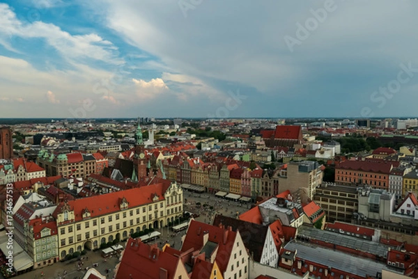 Obraz Aerial view of Wroclaw's colorful rooftops and historic buildings in Poland, showcasing the vibrant architecture of the city's Old Town square under a partly cloudy sky.