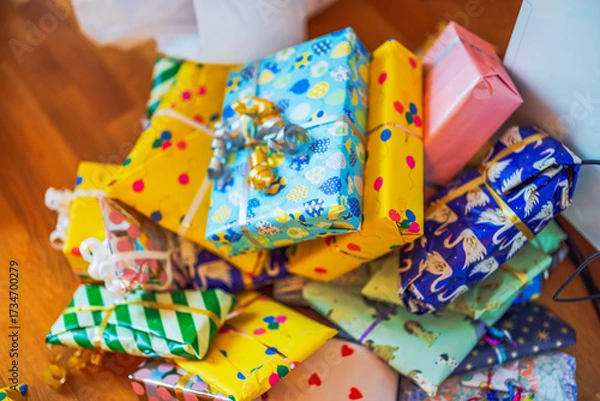 Fototapeta Close up view of children gifts wrapped in colorful paper with ribbons lying on wooden floor. Sweden.