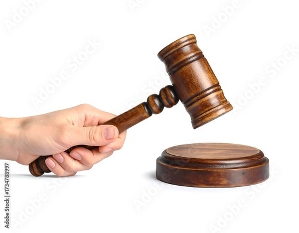 Fototapeta A hand holds a wooden gavel poised above a circular wooden block, isolated against a plain white background.