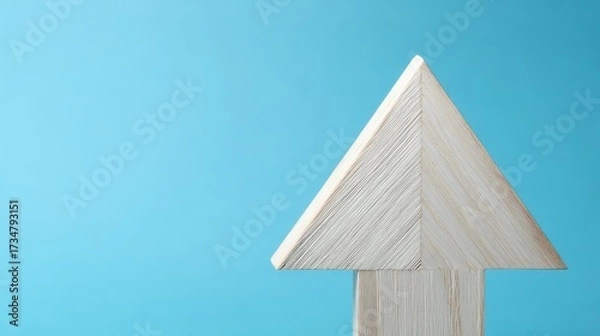 Fototapeta A light wooden arrow pointing upwards against a vibrant blue backdrop symbolizes growth, direction, and progress, creating a sense of upward momentum and positive trajectory.
