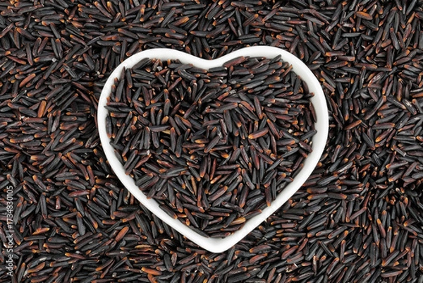 Fototapeta Black rice in a ceramic bowl as a background. Top view. Flat lay