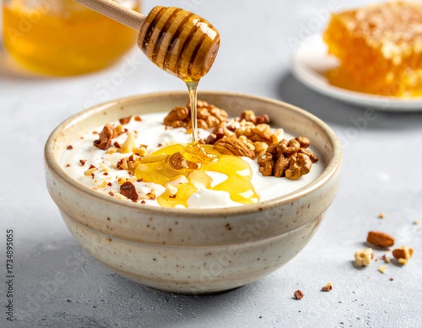 Fototapeta Golden Honey Drizzling Over Yogurt with Walnuts, Healthy Breakfast Scene.