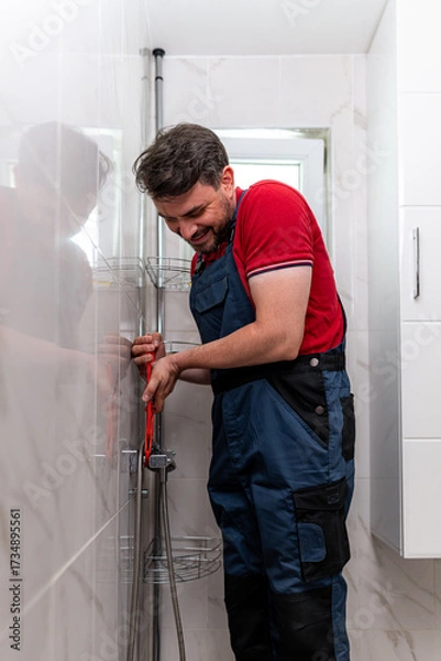 Fototapeta Plumber working on plumbing installation in modern bathroom at home during daylight hours