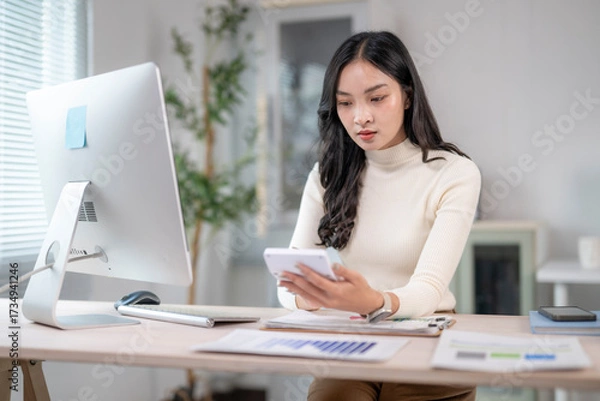 Fototapeta Businesswoman calculating tax using calculator at office desk