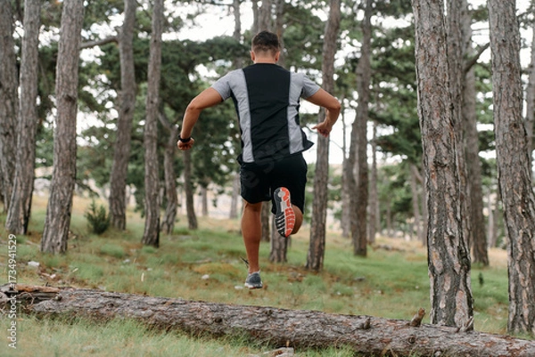 Fototapeta Determined Man Conquering Forest Obstacles with Grit and Speed