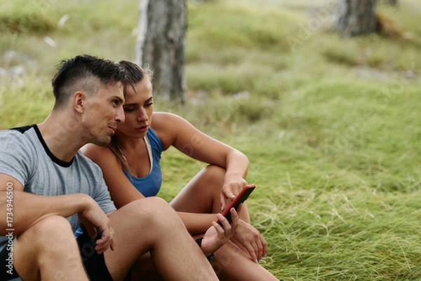 Fototapeta Romantic Couple Planning New Running Routes in the Forest with Smartphone