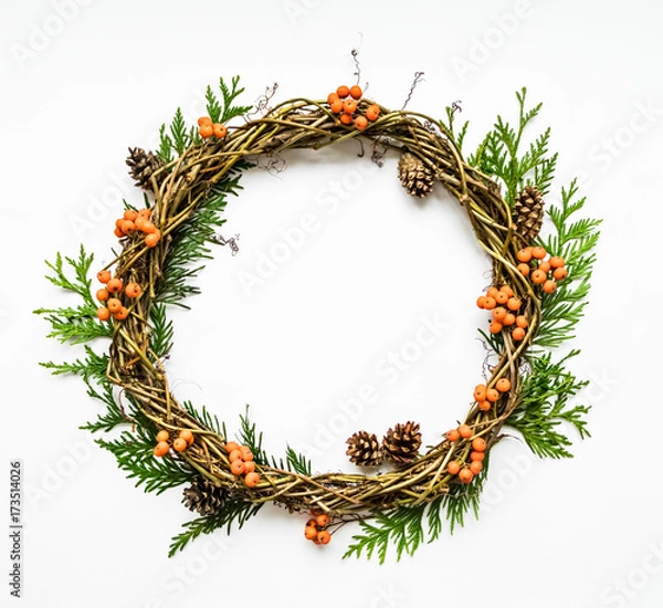 Fototapeta Festive wreath of vines with thuja branches, rowanberries and cones. Flat lay, top view