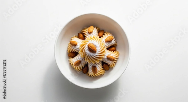 Fototapeta Almond cookies with powdered sugar in white bowl on white background, delicious snack