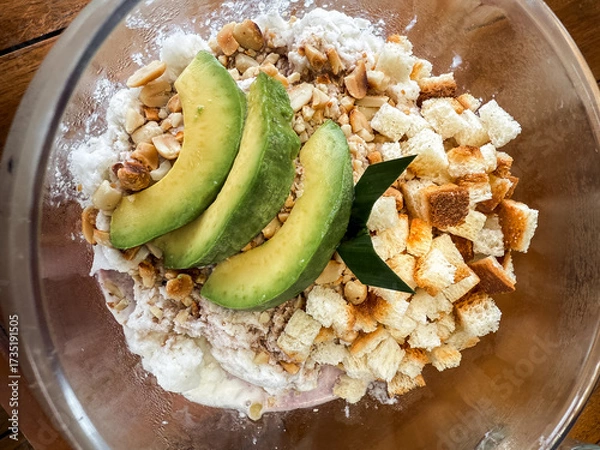 Fototapeta Refreshing Indonesian iced dessert "Es Campur" served in a glass bowl with avocado, jelly, bread cubes, and shaved ice. A colorful tropical treat perfect for hot days.