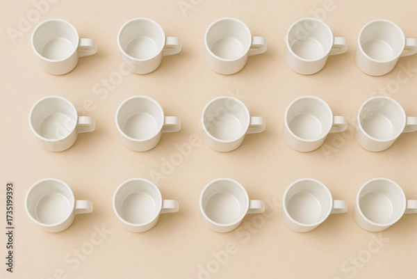 Fototapeta Minimalist coffee cup grid arranged in simple composition, showcasing empty white cups on soft beige background. This design evokes sense of calm and order