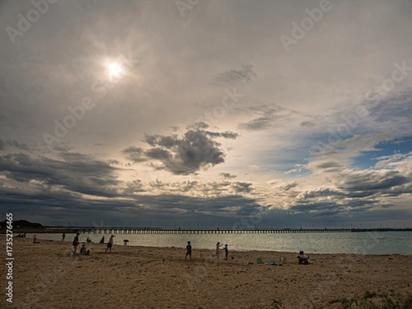 Fototapeta Playing On The Beach Before A Long Pier