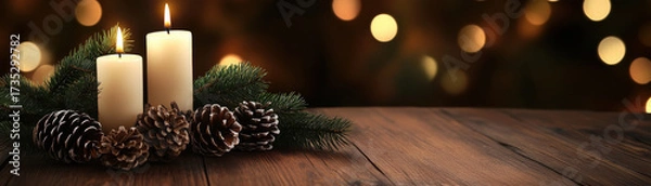 Fototapeta Cozy holiday setup with glowing candles, pine cones, and evergreen branches on wooden surface with warm bokeh lights in background
