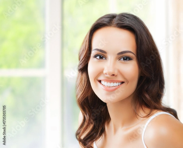 Fototapeta Portrait image of young cute dark brunette wavy hair woman cheerful smiling confidently at camera, set against window background with blurred greenery, home