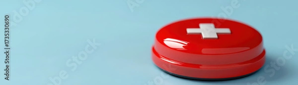 Fototapeta Glossy red medical emergency button with white cross symbol on light blue background, representing urgent healthcare or first aid concept