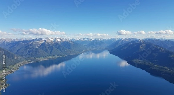 Fototapeta Aerial view of a vast lake with mountains reflecting in the calm water under a clear blue sky
