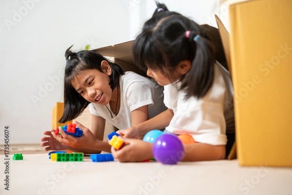 Fototapeta Playful Duo: Two young girls immerse themselves in a world of imaginative play. Surrounded by colorful toys and crafting materials, they build, create, and share moments of laughter and wonder.