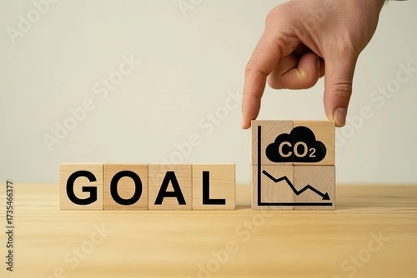 Fototapeta Hand places co2 reduction goal block next to word goal with downward trend graph