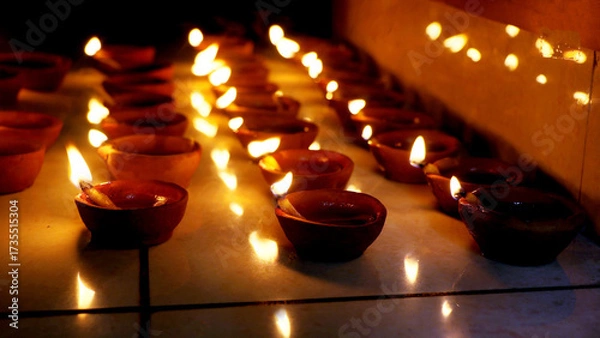 Fototapeta Rows of Lit Clay Oil Lamps Creating Warm Festival Glow