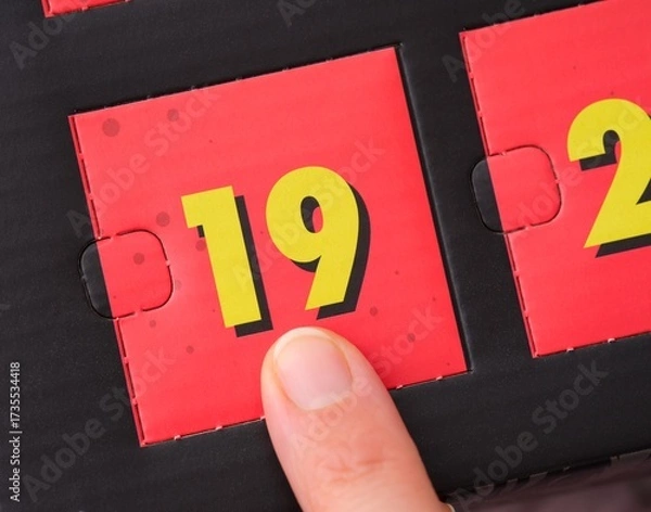 Fototapeta Woman finger pointing at the number 19 on an advent calendar.