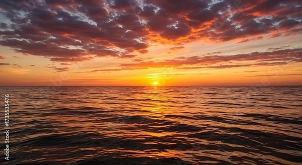 Fototapeta Vibrant sunset over ocean with fiery sky and water reflections