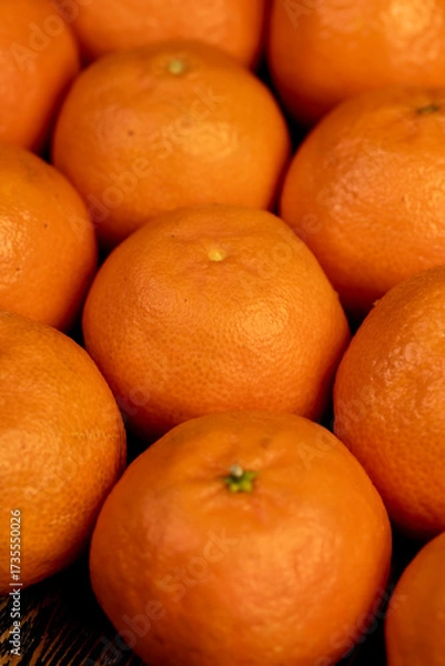 Fototapeta Unpeeled orange tangerines stacked together, a large number of ripe tangerines on the table