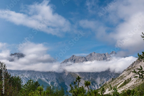 Obraz Alpine mountain peaks emerging above a drifting cloud layer