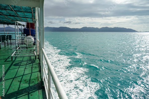 Obraz Ferry and Ferry pier near Koh Phangan island in Thailand. The rear of Ferries transport passengers. The beautiful scenery turquoise sea. Big ferry ship with Thai flag turning at the sea and sails.