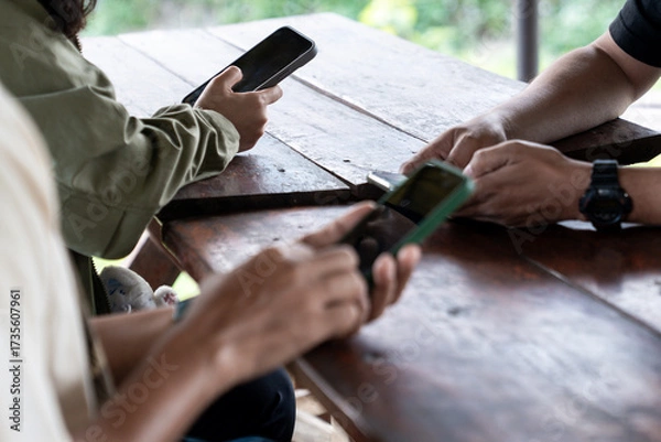Fototapeta A group of people sitting together but focused on their own smartphones, showing modern lifestyle and digital communication habits