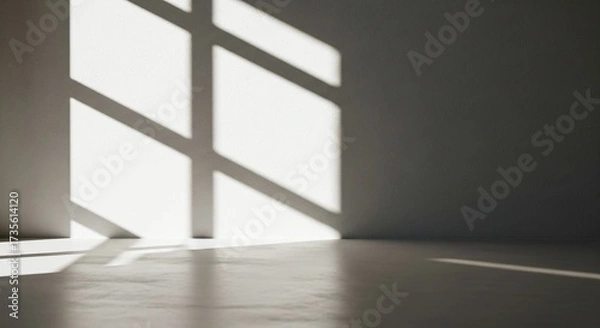 Fototapeta Sunlight streams through a window casting geometric shadows on the wall and floor of an empty room.