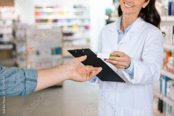 Fototapeta Unrecognizable woman pharmacist giving pills to client